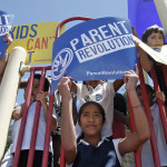 Children hold up “Parent Revolution” signs during a press conference held next to Desert Trails Preparatory Academy in Adelanto in 2013. Parents used a state law to transform their local low-performing public elementary school into a not-for-profit charter campus. (Los Angeles Times)
